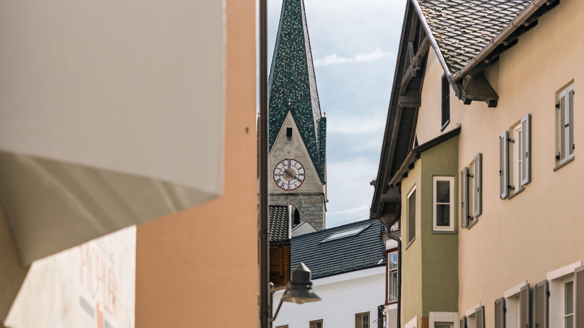Mühlbach in the Pustertal valley Church tower with clock viewed through a narrow alley between buildings