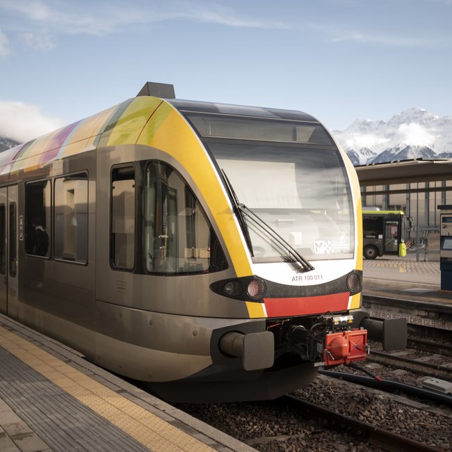 The eco-friendly way to enjoy South Tyrol Modern train at station with snowy mountains in background