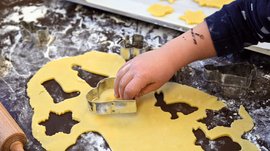 Tearna Advent Kind formt Keksteig mit Ausstechformen auf bemehltem Tisch