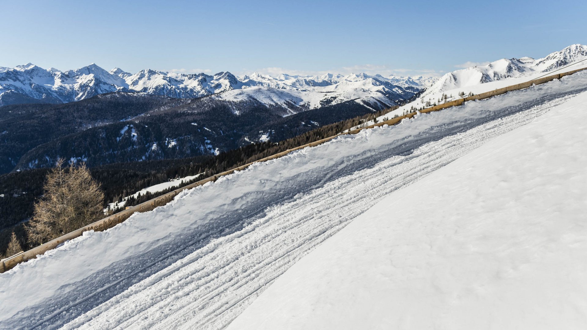 Rodeln in Südtirol Verschneite Skipiste mit Bergpanorama und klarem Himmel